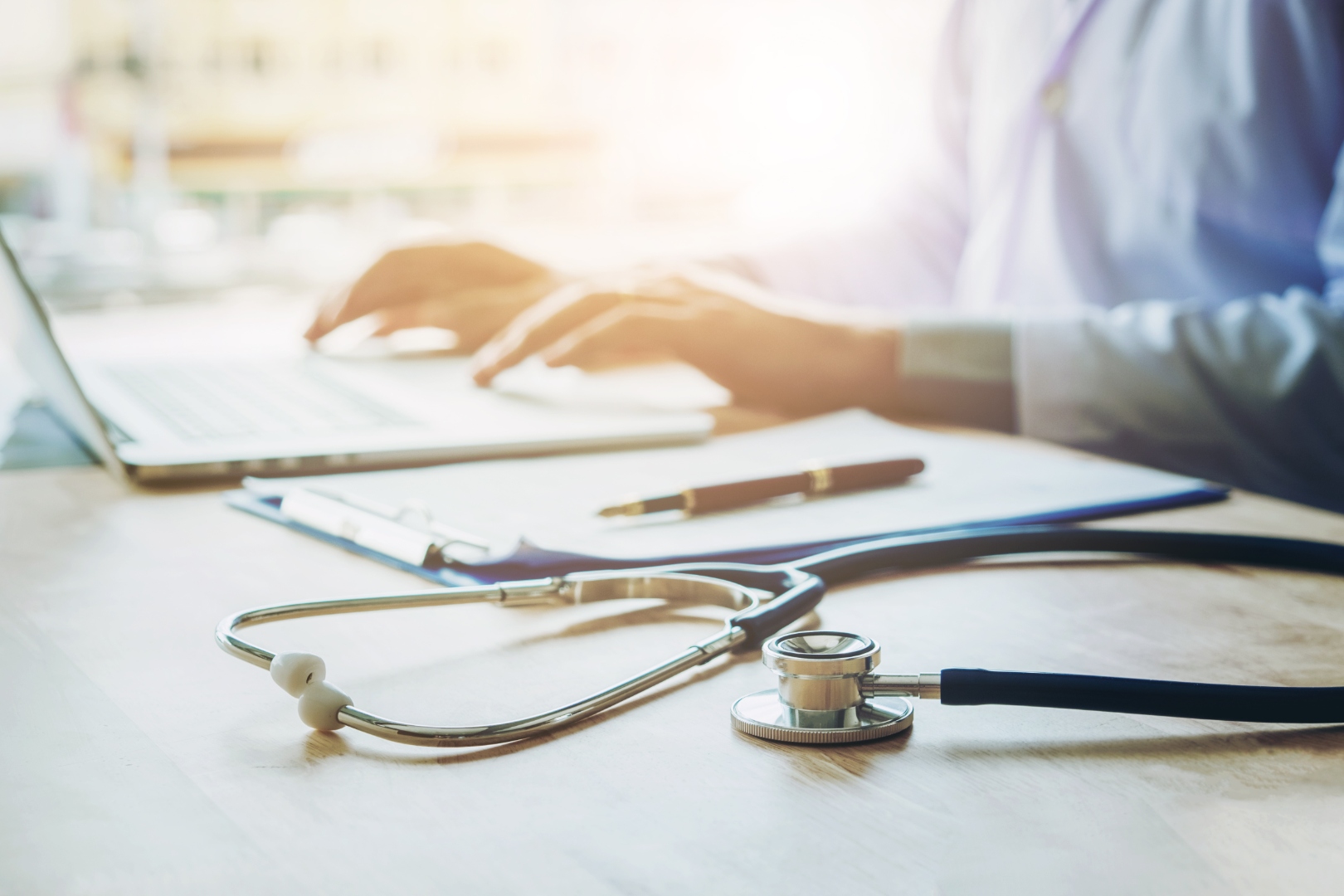 Stethoscope and healthcare professional using a laptop